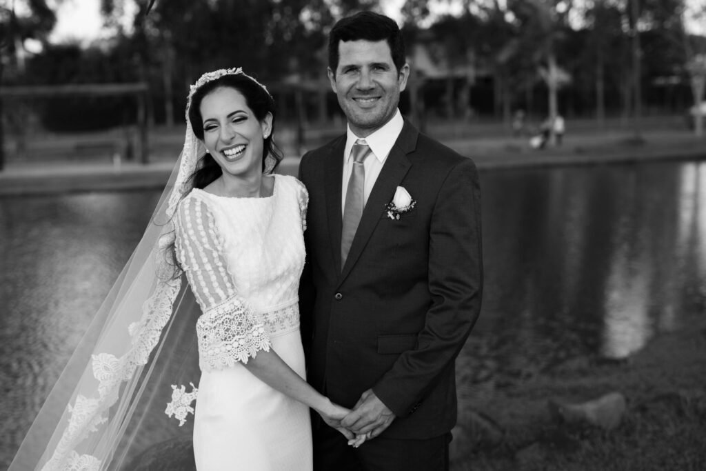 Happy bride and groom smiling by the riverside on their wedding day.