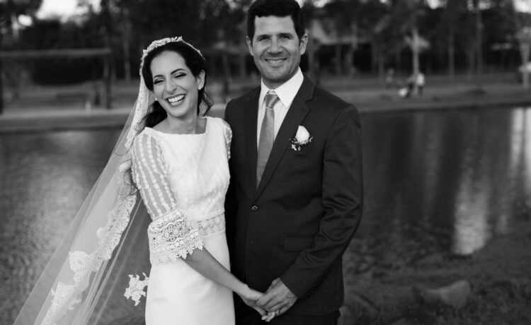 Happy bride and groom smiling by the riverside on their wedding day.