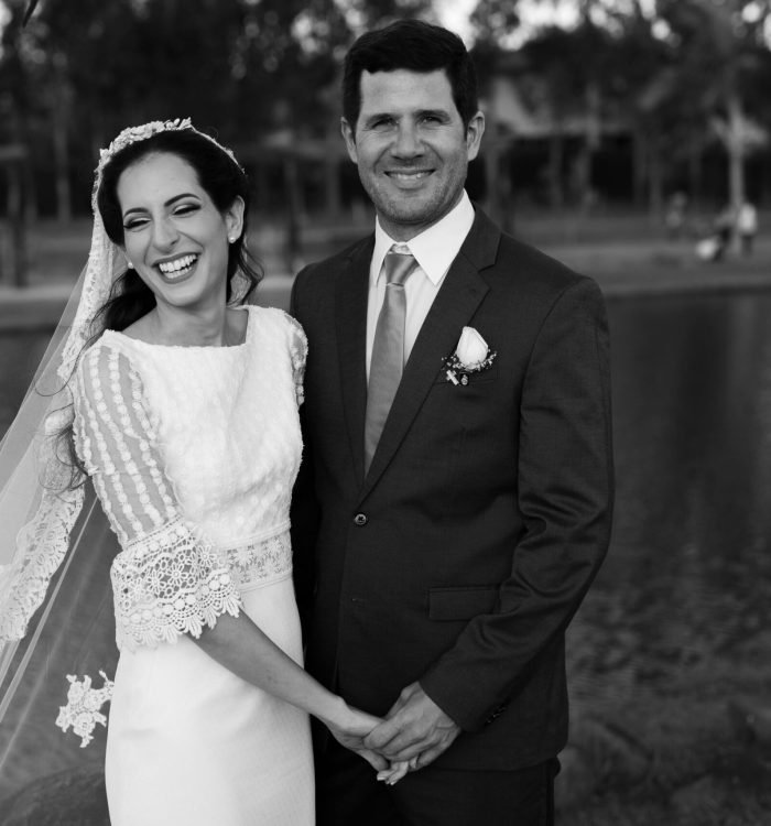 Happy bride and groom smiling by the riverside on their wedding day.